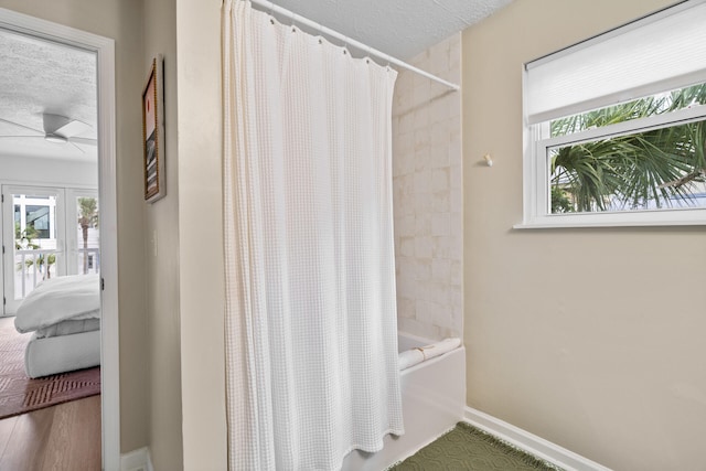 ensuite bathroom featuring a ceiling fan, a textured ceiling, shower / bath combination with curtain, and ensuite bath