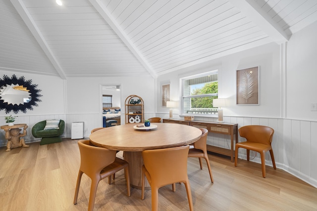 dining room with light wood-style floors, wooden ceiling, lofted ceiling with beams, and a wainscoted wall