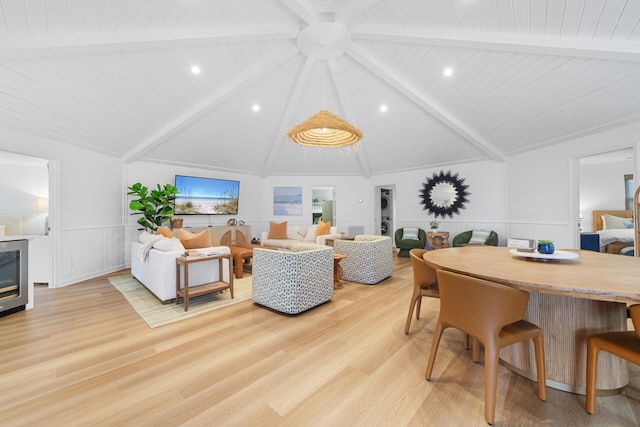 living area featuring lofted ceiling with beams, wooden ceiling, light wood-style flooring, and a wainscoted wall