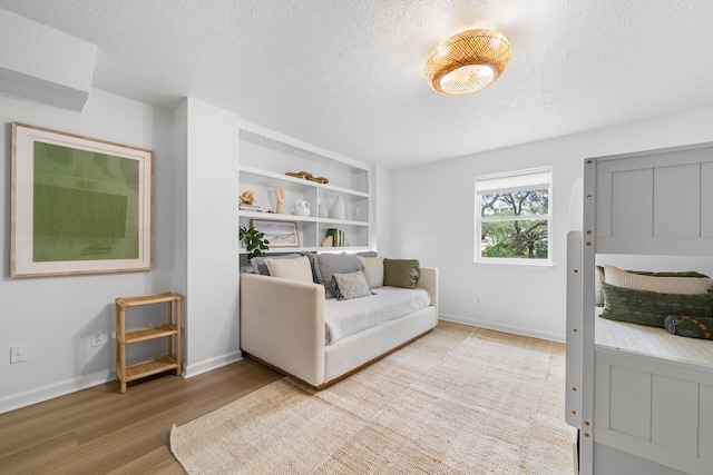 living room with baseboards, a textured ceiling, and light wood finished floors