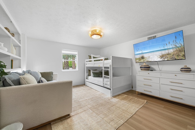 bedroom featuring visible vents, a textured ceiling, and light wood-style flooring