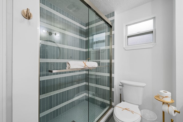 full bath with a shower stall, toilet, and a textured ceiling