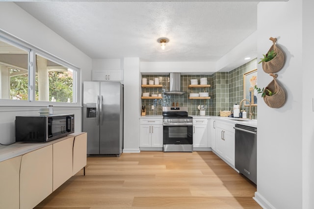 kitchen with open shelves, decorative backsplash, wall chimney range hood, a sink, and appliances with stainless steel finishes