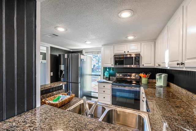 kitchen featuring a sink, stainless steel appliances, a textured ceiling, visible vents, and white cabinets