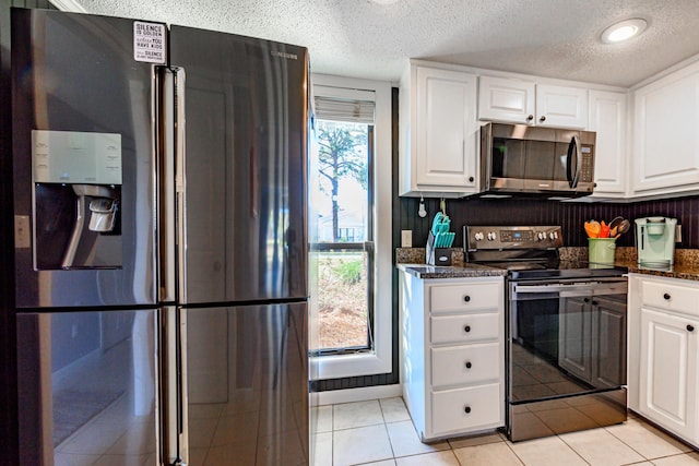 kitchen featuring stainless steel appliances, white cabinetry, light tile patterned flooring, and a textured ceiling