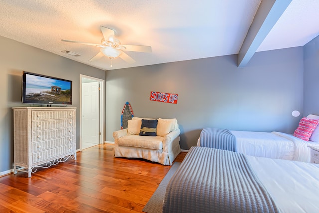 bedroom featuring baseboards, visible vents, a ceiling fan, and wood finished floors