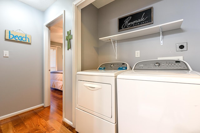 laundry room featuring baseboards, laundry area, light wood-type flooring, and washer and clothes dryer