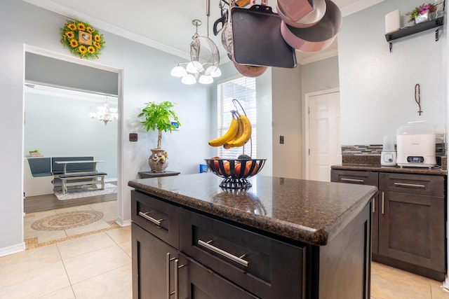 kitchen featuring ornamental molding, dark stone countertops, a kitchen island, and light tile patterned flooring