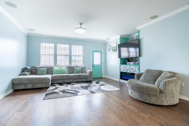 living room with baseboards, ornamental molding, a glass covered fireplace, and wood finished floors