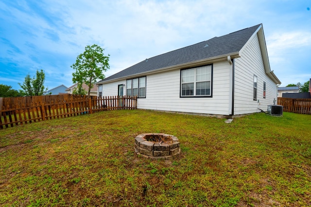 back of house featuring a yard, a fire pit, a fenced backyard, and central air condition unit