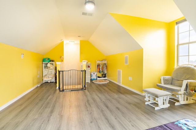 additional living space with visible vents, wood finished floors, and vaulted ceiling