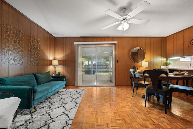 living room featuring a ceiling fan and wooden walls