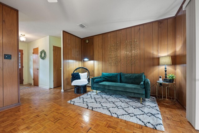 living room featuring wood walls, visible vents, and baseboards