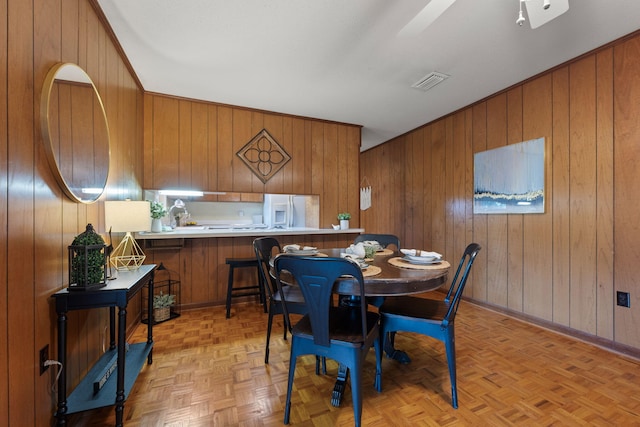 dining space with wooden walls, baseboards, and visible vents