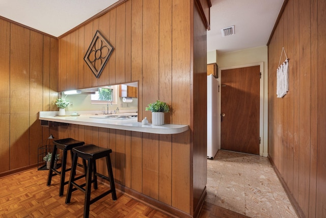 kitchen featuring brown cabinets, wooden walls, and visible vents