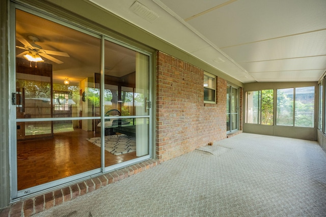 unfurnished sunroom with a ceiling fan and visible vents