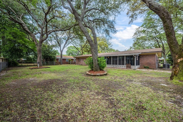 view of yard featuring central AC unit, a fenced backyard, and a sunroom