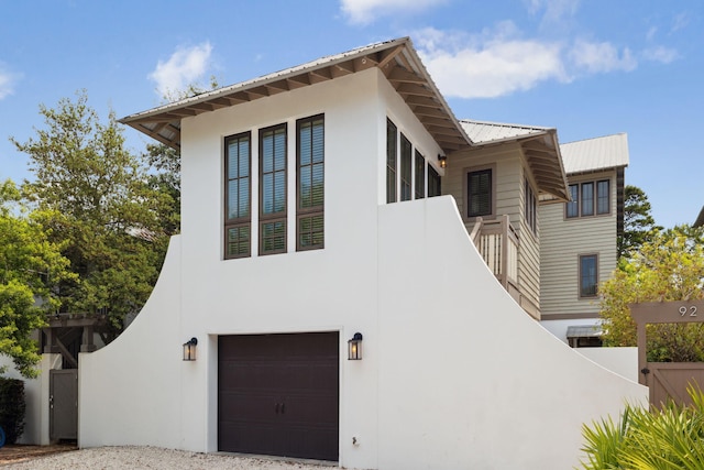 view of front of property with stucco siding, fence, metal roof, and a garage