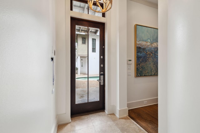 entrance foyer with baseboards, light tile patterned floors, a wealth of natural light, and an inviting chandelier