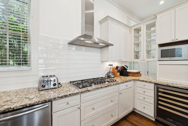 kitchen featuring wine cooler, glass insert cabinets, wall chimney exhaust hood, white cabinetry, and appliances with stainless steel finishes