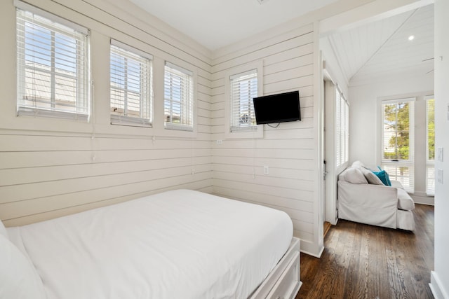 bedroom featuring wood walls, dark wood finished floors, and lofted ceiling