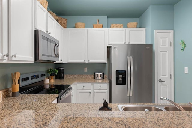 kitchen with a sink, white cabinets, light stone countertops, and stainless steel appliances