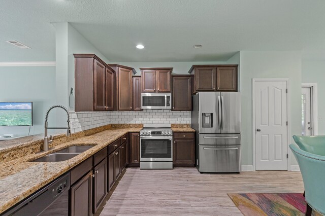 114 Rearden Way, Santa Rosa Beach, FL 32459 - kitchen featuring appliances with stainless steel finishes, a sink, light stone countertops, dark brown cabinets, and backsplash