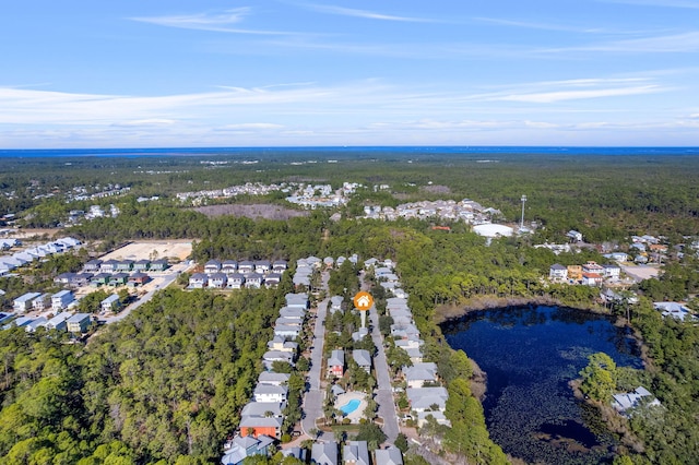aerial view of property and surrounding area featuring nearby suburban area, a forest, and a nearby body of water