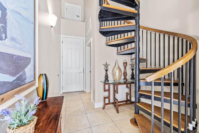 foyer entrance with stairway, baseboards, and tile patterned floors