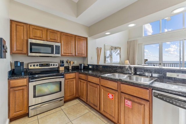kitchen featuring a sink, brown cabinetry, stainless steel appliances, and light tile patterned flooring