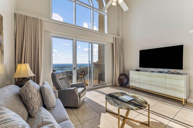 tiled living area featuring baseboards, ceiling fan, and a towering ceiling