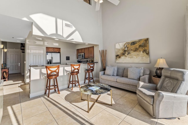 living room featuring light tile patterned floors, visible vents, baseboards, and ceiling fan