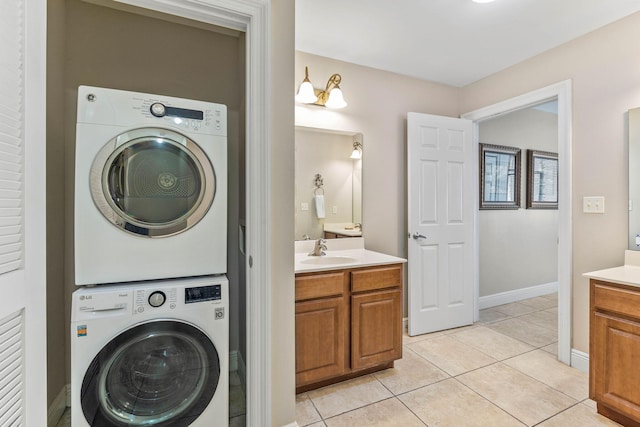 washroom with a sink, stacked washing maching and dryer, laundry area, and light tile patterned floors