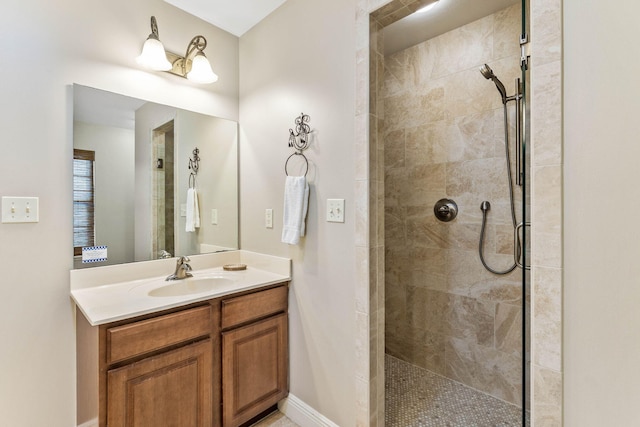 full bath with vanity, baseboards, and tiled shower