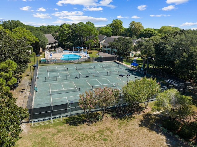 view of tennis court featuring fence and an outdoor pool