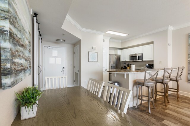 16819 Front Beach Rd Unit 2415, Panama City Beach, FL 32413 - kitchen with appliances with stainless steel finishes, a peninsula, a kitchen bar, white cabinets, and light wood-style floors