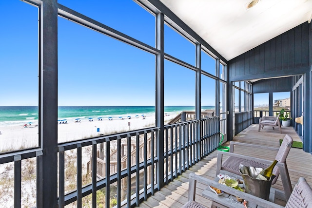 sunroom featuring a water view and a beach view
