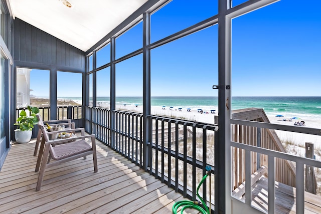 sunroom with a water view and a view of the beach
