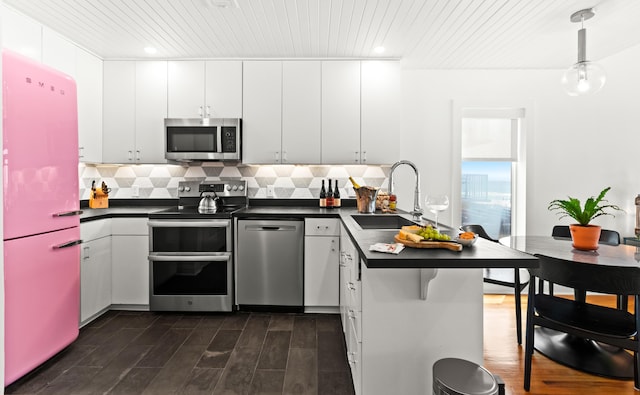 kitchen featuring a sink, wood ceiling, dark countertops, and appliances with stainless steel finishes