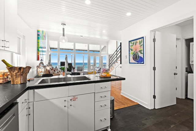 kitchen featuring white cabinets, dark countertops, open floor plan, and a sink