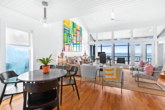 dining space with a water view, light wood-type flooring, and a ceiling fan