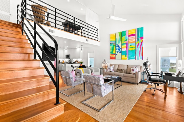 living room with visible vents, wood finished floors, a high ceiling, and stairs
