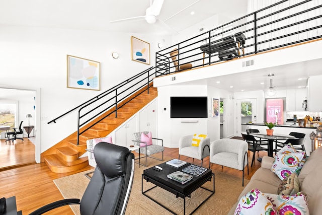 living room with ceiling fan, stairway, visible vents, and wood finished floors