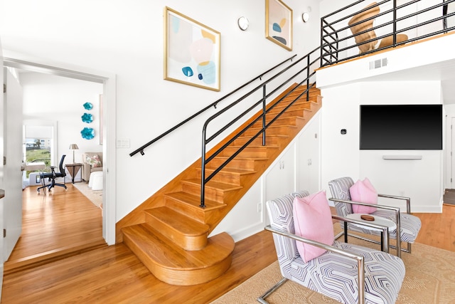stairs with visible vents, wood finished floors, and a towering ceiling