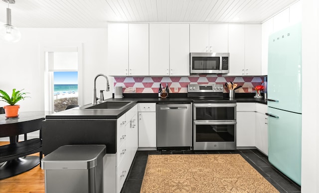 kitchen with white cabinets, appliances with stainless steel finishes, a sink, and tasteful backsplash
