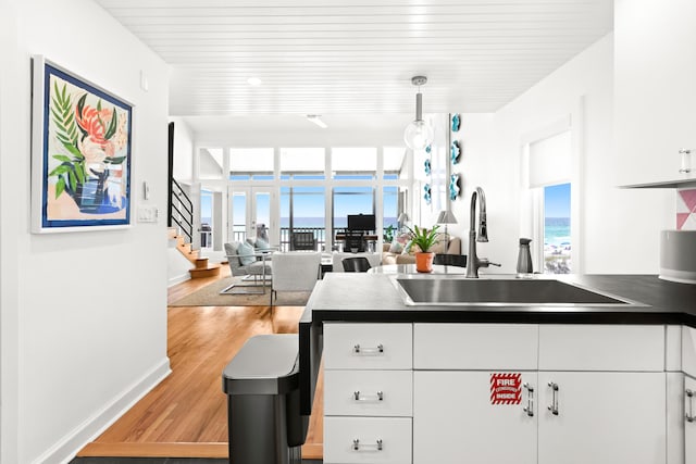 kitchen featuring dark countertops, white cabinetry, light wood-type flooring, and a sink