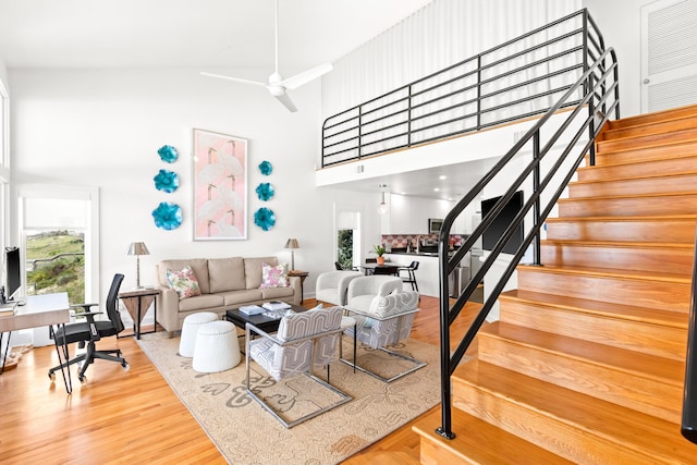 living room featuring wood finished floors, a towering ceiling, a healthy amount of sunlight, and stairs