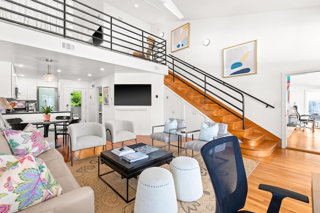 living room with stairs, a wealth of natural light, visible vents, and wood finished floors