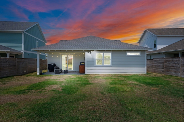 2108 Royal Tern St, Panama City, FL 32405 - back of property at dusk with a fenced backyard, a lawn, and roof with shingles