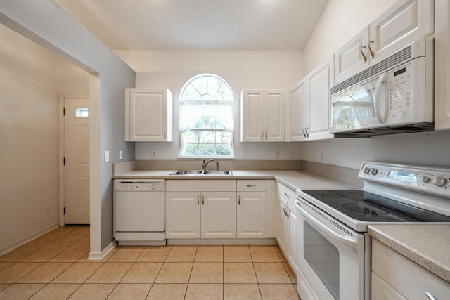 kitchen with a sink, white appliances, light countertops, light tile patterned floors, and white cabinets